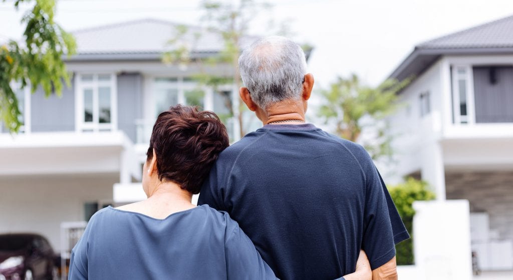 Back of couple standing in front of home, loan forbearance for senior homeowners